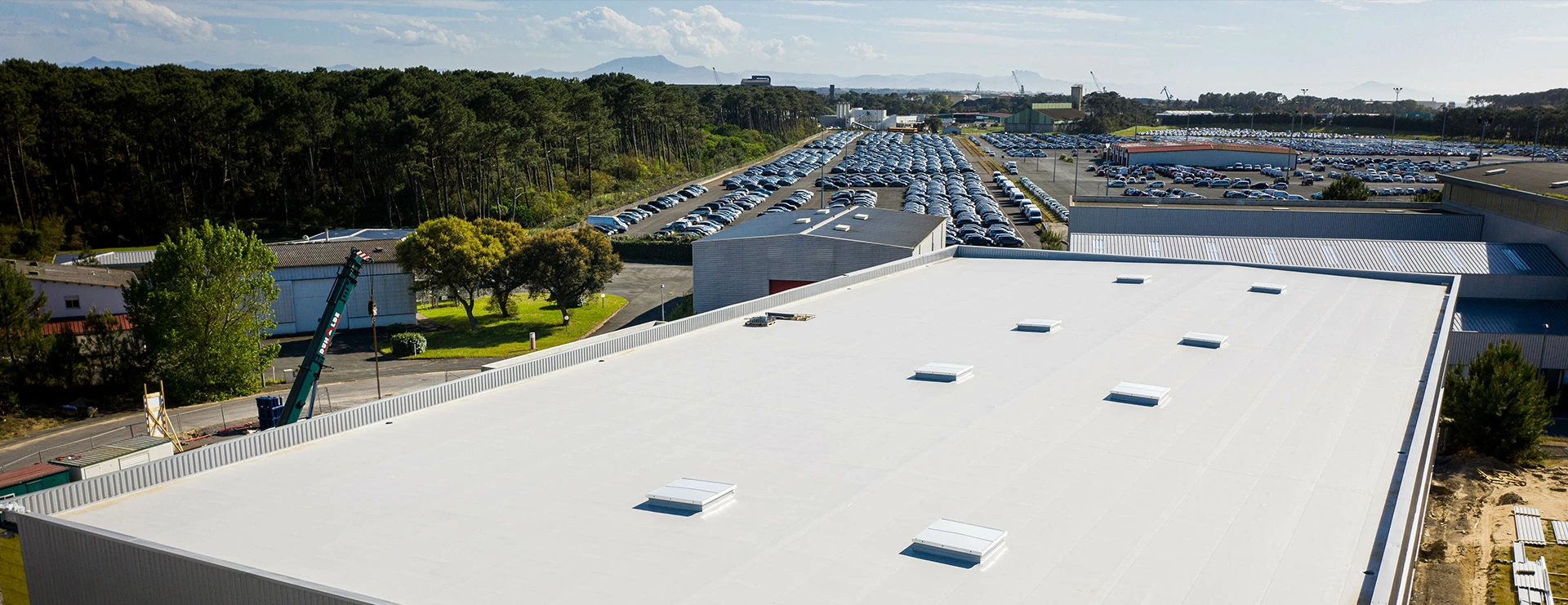 Toiture industrielle plate blanche rénovée par Etancheite Em Aquitaine à Bordeaux, vue aérienne de zone logistique